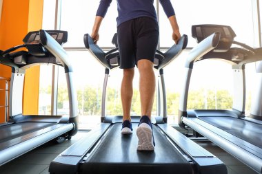 Genç adam spor salonunda koşu bandında antrenman yapıyor.