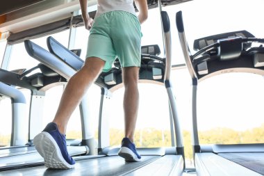 Genç adam spor salonunda koşu bandında antrenman yapıyor.