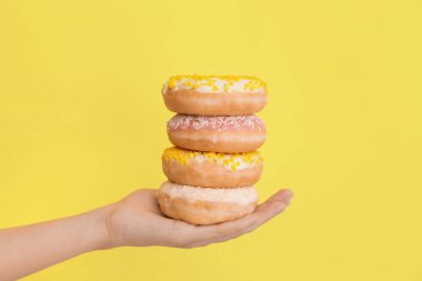 Renkli arka planda tatlı donutları olan el.