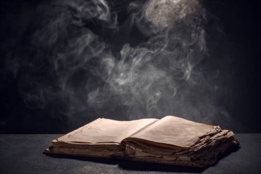 Koyu arka plan karşı masada açık kitap