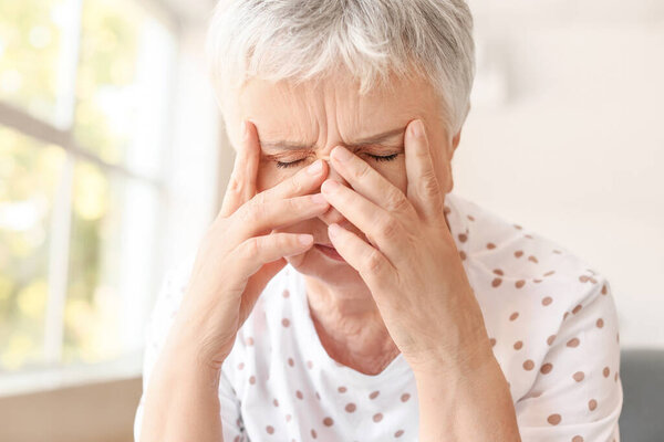 Stressed senior woman suffering from headache