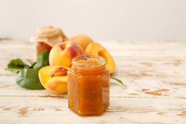 Ahşap masada şeftali reçelli kavanoz.