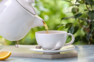 Çaydanlıktan çayı bulanık arka planda masanın üzerine dökmek