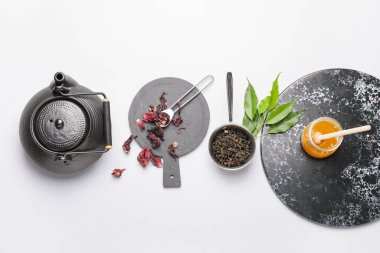 Çaydanlık, bal ve kuru çay yapraklarıyla beyaz arka planda kompozisyon