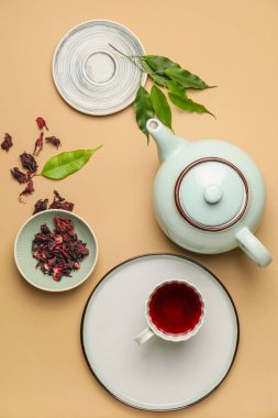 Çaydanlık ve arkaplan renginde bir fincan amberçiçeği çayı ile kompozisyon