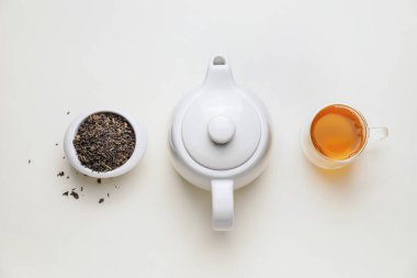Çaydanlıklı kompozisyon, bir fincan çay ve beyaz arka planda kuru yapraklar.