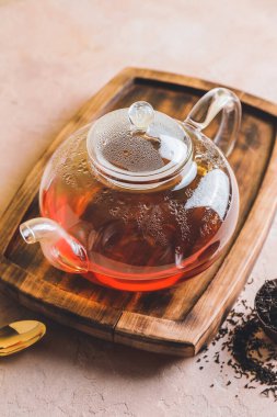 Cam çaydanlık ve kuru çay yaprakları masada.