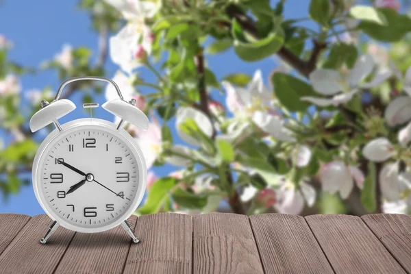 開花庭のテーブルの上の目覚まし時計 時間変化の概念 — ストック写真
