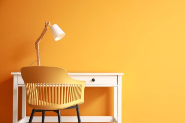 Renkli duvarın yanında lamba ve sandalye olan modern masa