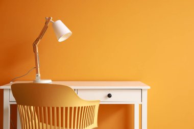 Renkli duvarın yanında lamba ve sandalye olan modern masa