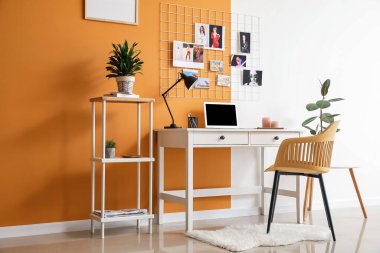 Renk duvarının yanında modern dizüstü bilgisayarı olan rahat bir iş yeri