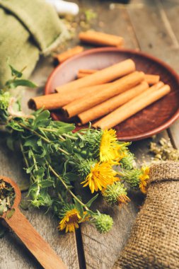 Tahta arka planda taze bitkiler ve tarçın, yakın plan.