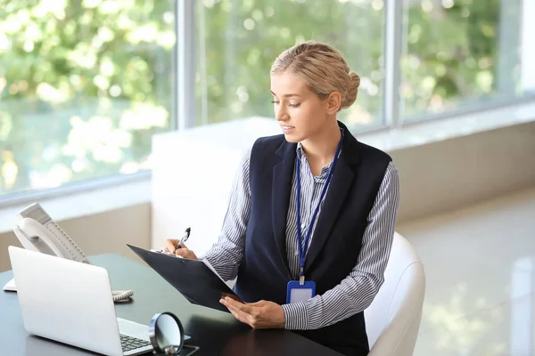 Young woman with blank badge in office