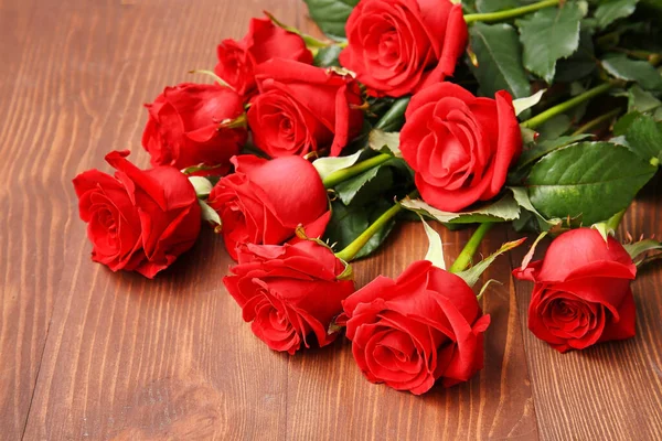 木制背景上的一束美丽的红玫瑰 — 图库照片