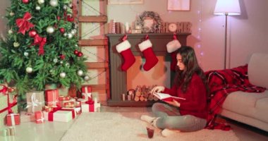 Noel arifesinde şöminenin yanında kitap okuyan bir kadın.