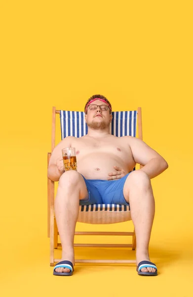 Överviktig Man Med Glas Sitter Stranden Stol Mot Färg Bakgrund — Stockfoto