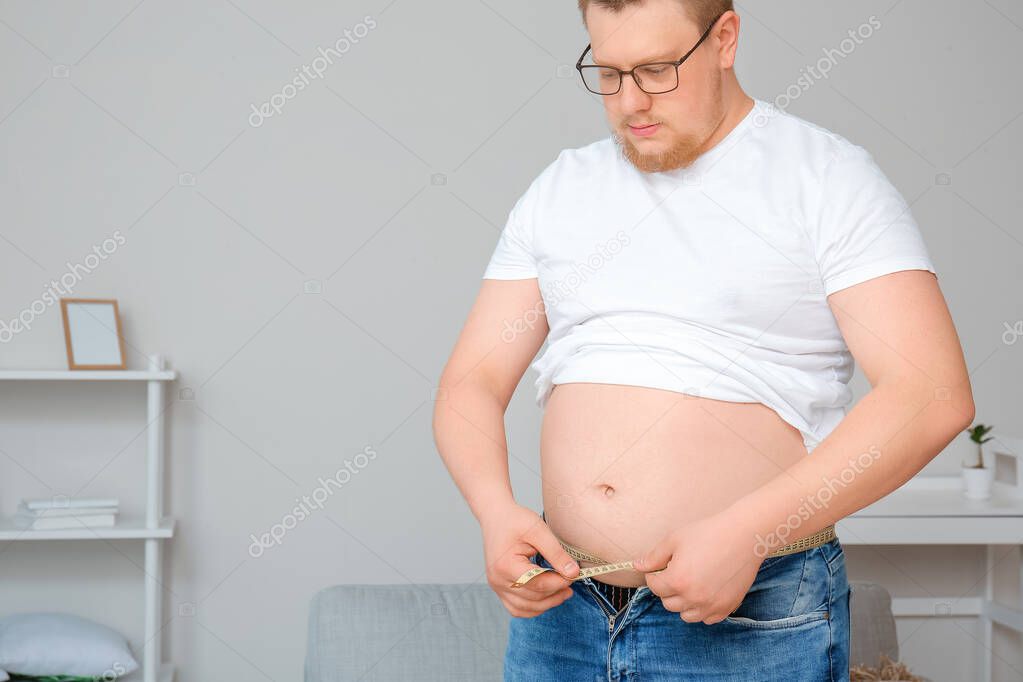 Overweight man with measuring tape at home. Weight loss concept
