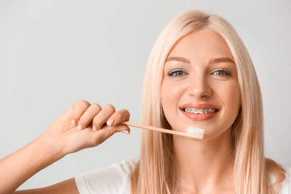 Jonge Vrouw Met Tandbeugels Houten Tandenborstel Lichte Achtergrond — Stockfoto