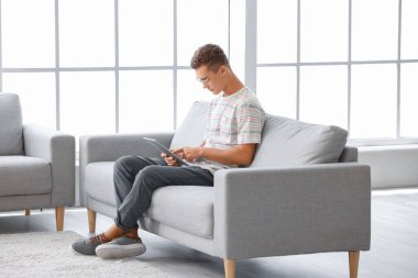 Evde tablet bilgisayarı olan genç bir çocuk.