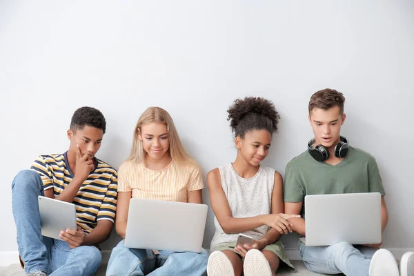 Tieners Met Verschillende Apparaten Buurt Van Een Lichtmuur — Stockfoto