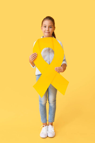 Little girl with golden ribbon on color background. Childhood cancer awareness concept