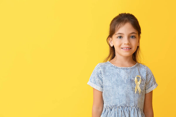 Little girl with golden ribbon on color background. Childhood cancer awareness concept