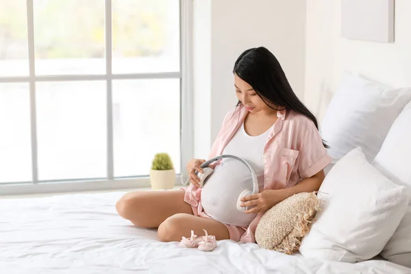 Pregnant Asian Woman Putting Headphones Her Belly Bedroom — Stock Photo, Image