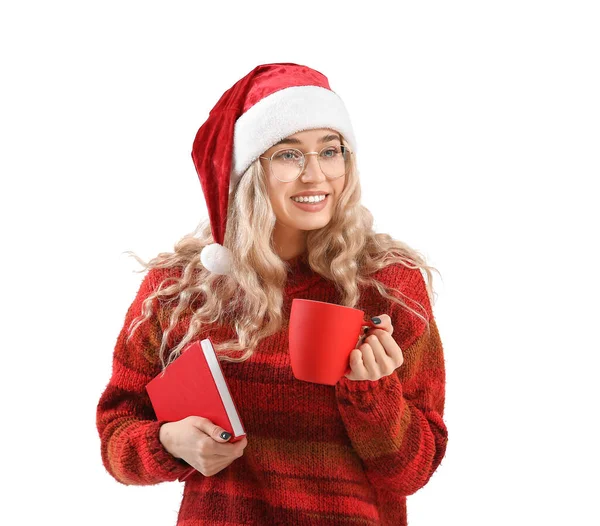 漂亮的年轻女子戴着圣诞老人的帽子 背景是白色的书本和杯子 — 图库照片