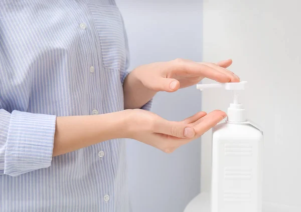 Young woman using sanitizer at home