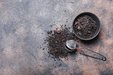 Kasede kuru siyah çay yaprakları ve grunge arka planda infuser