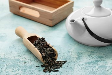 Renkli arkaplanda kepçeyle kuru siyah çay yaprakları