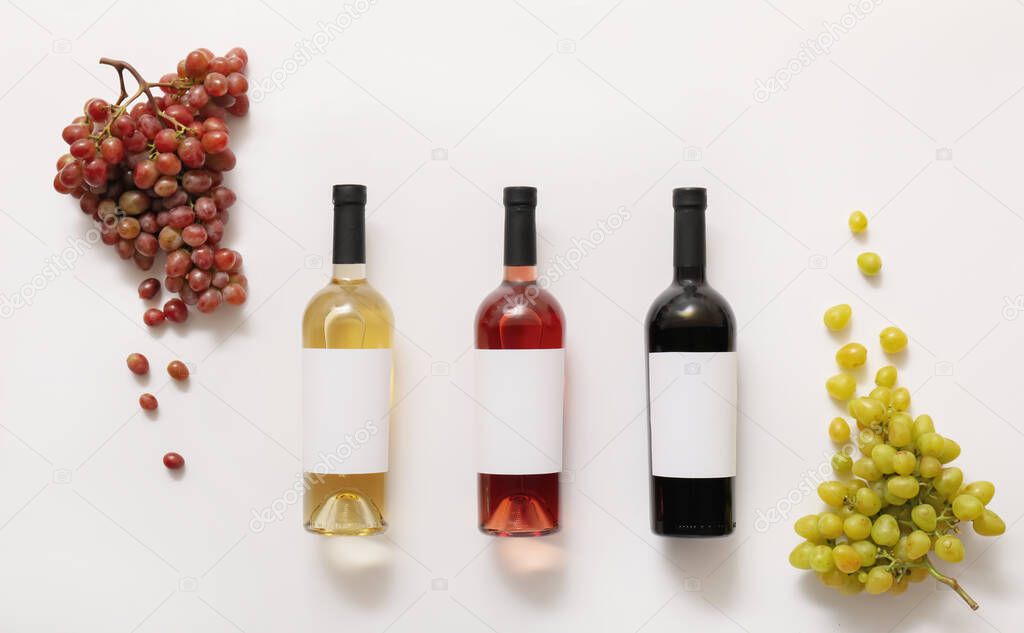 Bottles of wine with blank labels and grapes on white background