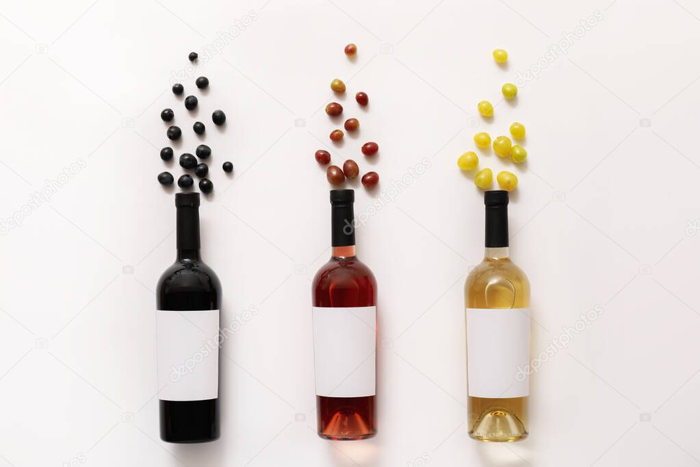 Bottles of wine with blank labels and grapes on white background