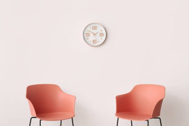 Koltuklar ışık duvarına dayanıyor ve modern saat odada.