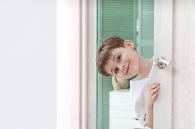 Kapıdan dışarı bakan sevimli küçük çocuk.