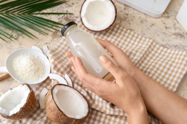 Masasında bir şişe taze hindistan cevizi suyu olan bir kadın.