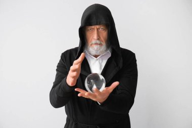 Işık arkaplanda kristal küresi olan erkek falcı.