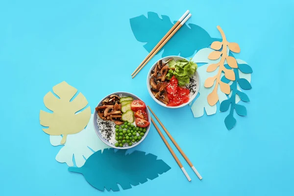 Bowls with tasty rice and vegetables on color background