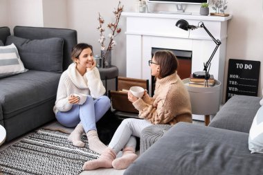 Evde şöminenin yanında çay içen genç kadınlar.