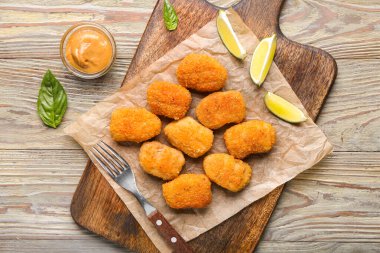 Ahşap arka planda lezzetli nuggetları olan tahta.