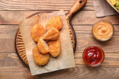 Ahşap arka planda lezzetli nuggetları olan tahta.