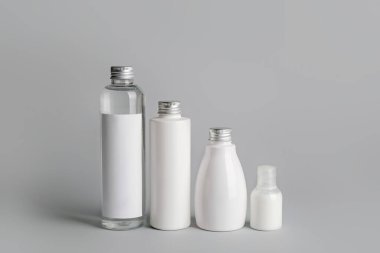 Gri arka planda farklı kozmetik ürünleri şişeleri