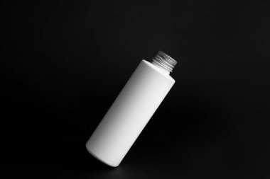 Siyah arkaplanda bir şişe kozmetik ürünü