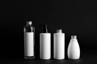 Siyah arka planda farklı kozmetik ürünleri şişeleri