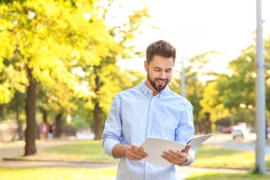 Açık havada boş dergileri olan genç bir adam.