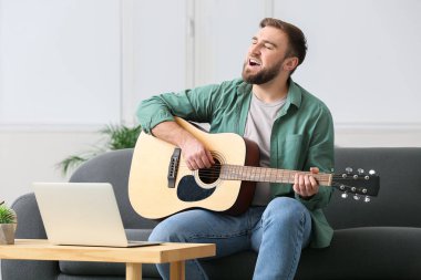 Genç adam evde online müzik dersleri alıyor.