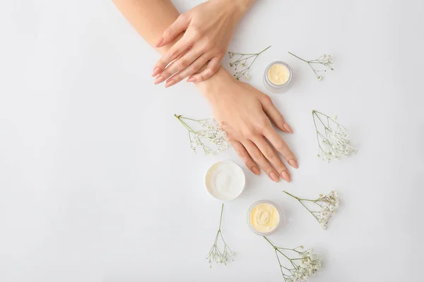 Mãos Femininas Com Creme Belas Flores Fundo Claro — Fotografia de Stock