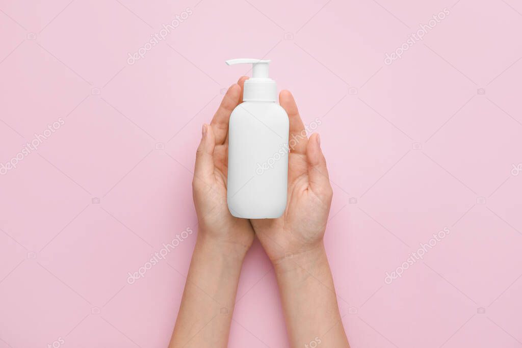 Female hands with cosmetic bottle on color background