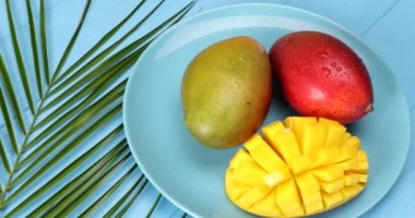 Renkli ahşap zemin üzerinde olgun mangoları olan bir tabak.