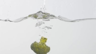 Hafif arkaplana karşı suya taze brokoli düşmesi